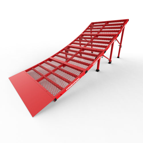 A red portable moto jump ramp made of metal with a grated surface, designed for motorbike launching and skills practice.