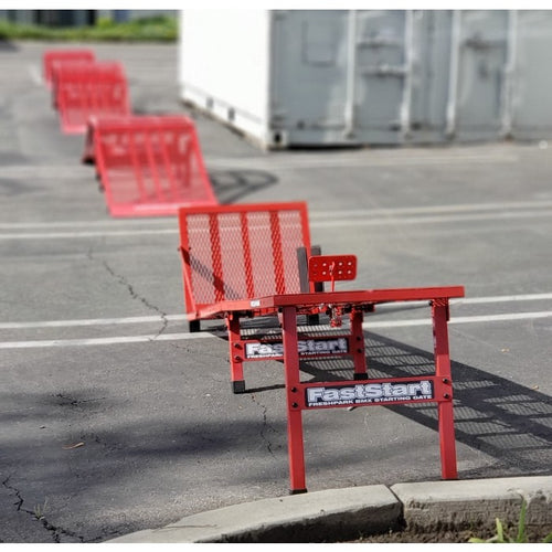 A red metal BMX starting gate with a 'FastStart' sign on it, placed on an asphalt surface.
